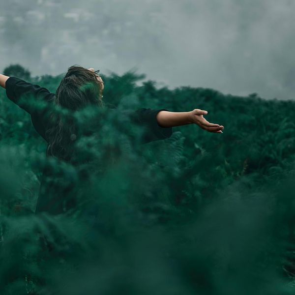 Person meditating peacefully in a green natural environment.